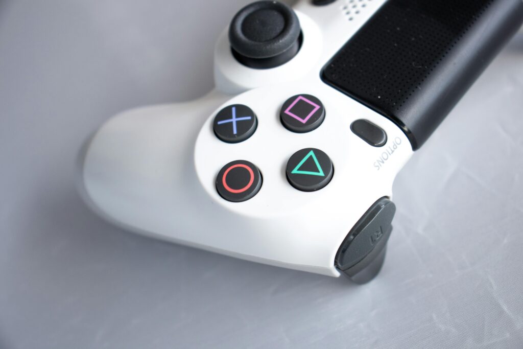 Close-up photo of a white PlayStation game controller on a gray background.