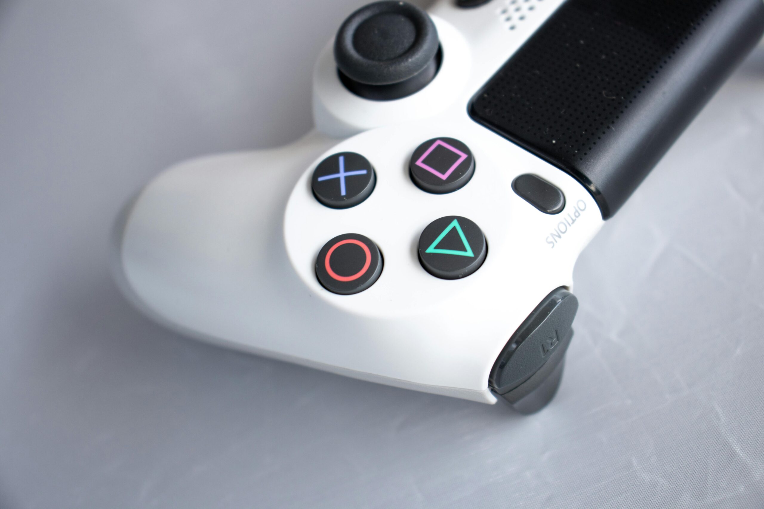 Close-up photo of a white PlayStation game controller on a gray background.